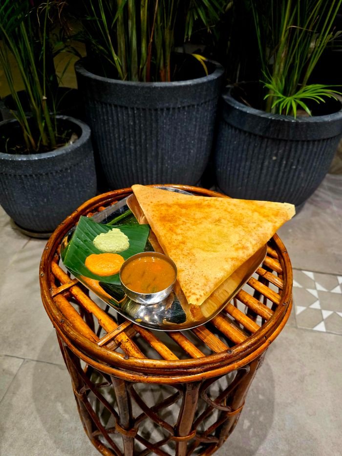 Crispy Indian dosa served with chutney and sambar on a rustic table, perfect for food lovers.